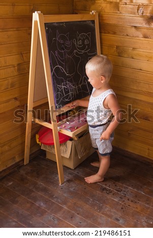 Young artist. Little boy drawing with chalk on a blackboard