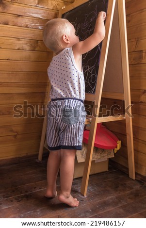 Young artist. Little boy drawing with chalk on a blackboard