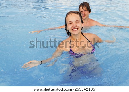 Happy boy and girl teens swim in the pool water park