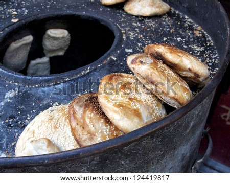 Toasted bao buns lined up on kettle with several more cooking in a Chinese street market