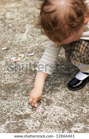 two year - child drawing on sidewalk with colored chalks