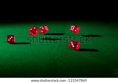 Five red dice rolling on the table with hard shadows