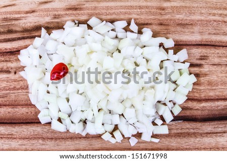 Diced White Onion.  Freshly cut white onion on a wooden chopping board, with a sole red chili