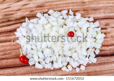 Diced White Onion with two red Chilis. A pile of freshly chopped white onion, garnished with two red chills, on a wooden chopping board