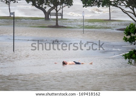 BRISBANE, QLD, AUSTRALIA - January 27: Man lies in flood water in Brisbane, during the floods of 27 January 2013