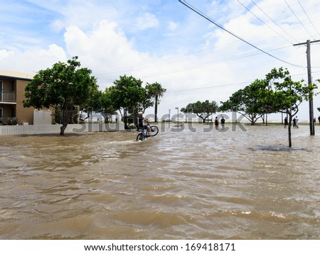 BRISBANE, QLD, AUSTRALIA - January 27: A man on a bicycle does a wheelie in the flooded street in Sandgate in the floods of 27 January 2013