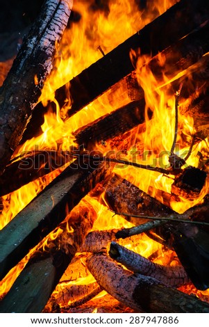 Burning fire with interlaced planks of wood forming triangle patterns.