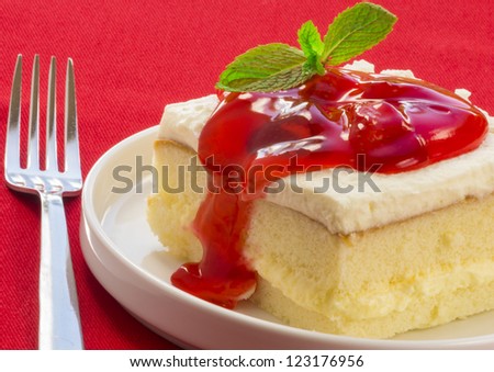 Square slice of strawberry shortcake on red tablecloth