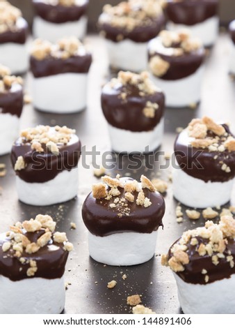 Traditional s\'mores deconstructed as marshmallows dipped in milk chocolate and topped with crumbled graham crackers
