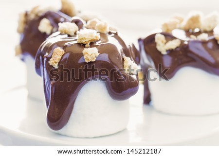 Traditional s\'mores deconstructed as marshmallows dipped in milk chocolate and topped with crumbled graham crackers
