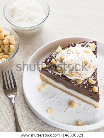 A decadent haupia and chocolate custard pie topped with shaved coconut, macadamia nuts and shaved chocolate, served with whipped cream
