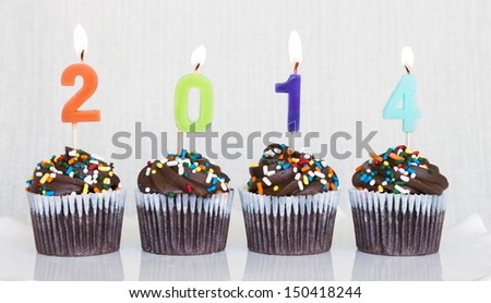 Lit multicolored candles that spell 2014 in chocolate mini cupcakes with colored sprinkles