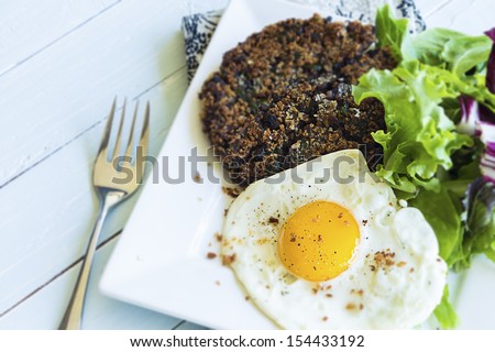 Healthy meal of black bean cake with mixed greens and a fried egg