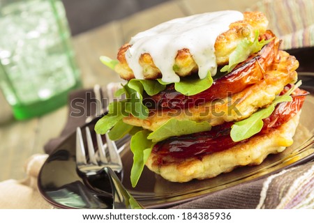 Corn fritters stacked with roasted tomatoes and arugula, served with ranch dressing