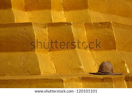Gold Pyramid. Workers straw hat left on top of a golden structure at a Buddhist temple.