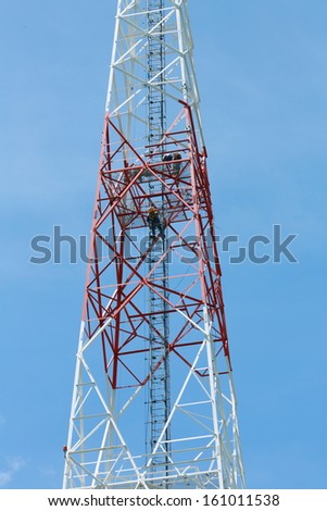 Communications Mast. Work team repairing a cell phone mast. Blue sky background on a clear day.