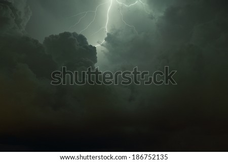 Thunderbolt and Lightning. Lightning flash illuminating the clouds on a dark night. Graduated shot from light to dark top to bottom. Shot has an almost religious quality.