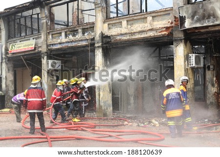 Georgetown Penang. Heritage Shop houses on Fire April 20th 2014. Firefighters on the scene tackling the blaze. Closeup of a fire team manning a hose.