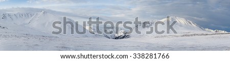 Winter landscape. Dramatic overcast sky.Severe mountains peaks covered by snow. Russia, Siberia, Altai mountains, Chuya ridge.