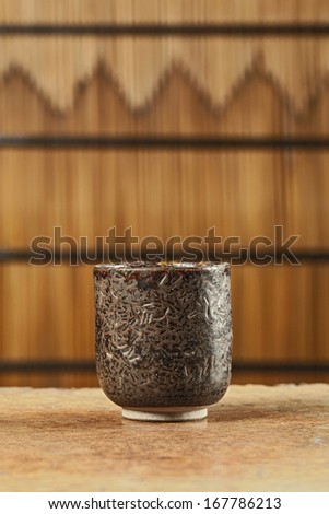 Ceramic striped cup on wooden table in bamboo screen (Still life)