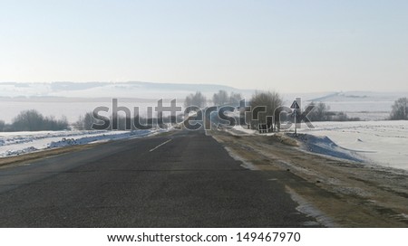 winter landscape paved road leading to the horizon and snow-covered fields