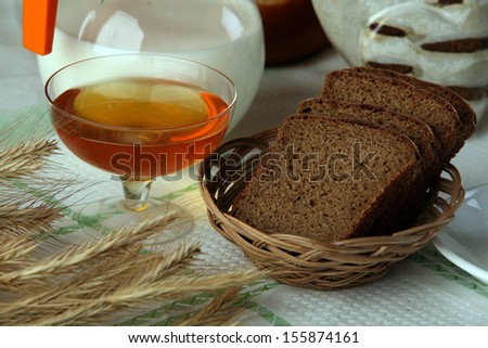 close-up of sliced brown bread, a jug of milk, a cup of tea and a figure of a cat in the studio on a brown background