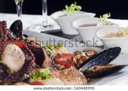 Macro still life white dish with seafood and wine glasses with white wine on a white tablecloth in a studio on a black background