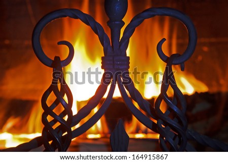close up of a beautiful wrought-iron grate against the bright flame and a brick wall