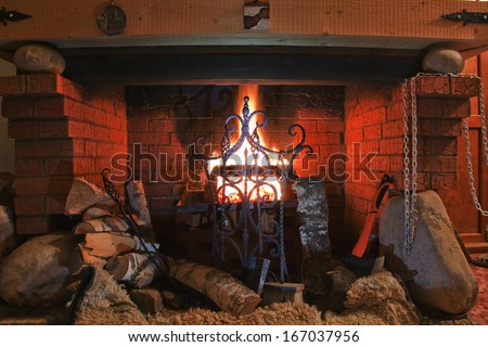 Close-up of brick fireplace with an iron gate with a bright flame burning logs