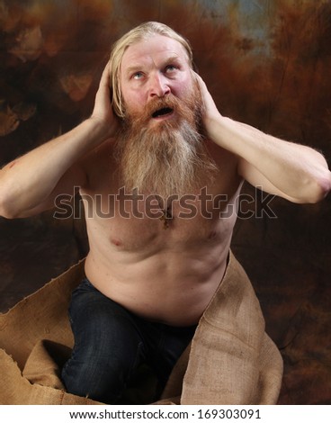 portrait of a naked man with a beard and a mustache on his knees, crying out to God, the studio on a brown-blue background