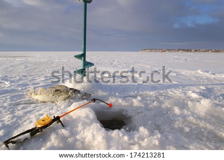 close-up boer, fishing rod and fish around the ice-hole on the winter river in a sunny day
