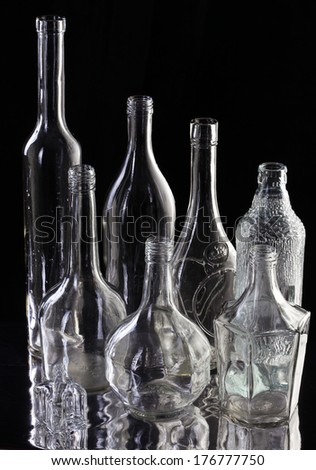 close-up beautiful transparent white empty bottles on the mirror surface on black background studio