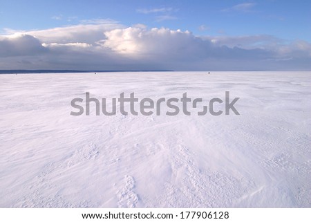 amazing winter landscape beneath the ice of a broad river and beautiful clouds in the blue sky