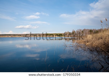landscape in early spring on the river and dry reeds along the bank of a clear, sunny morning