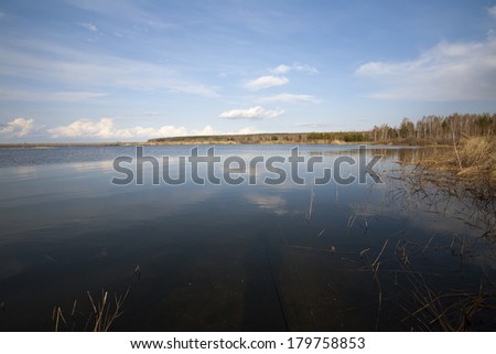 landscape in early spring on the river and dry reeds along the bank of a clear, sunny morning
