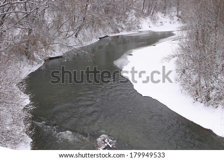 Winter landscape is not completely frozen river and trees with no leaves on the shore