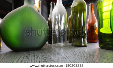 close-up colorful dusty bottles on a gray wooden floor in the studio on a background of light strip