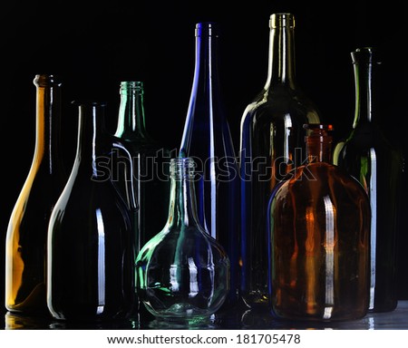 close-up collection of beautiful colored bottles of different shapes on a black background studio