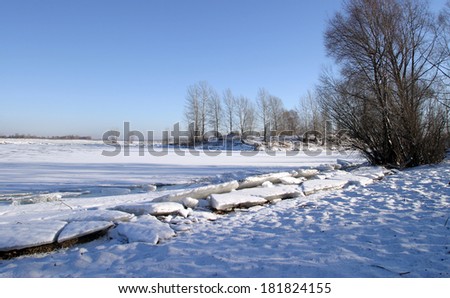 Winter landscape river of bright blue sky and trees on the shore on a sunny afternoon