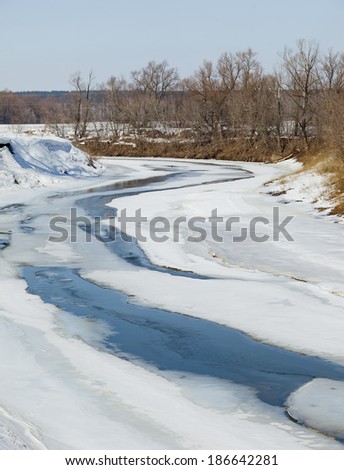 scenic landscape river trees without leaves on the shore and the melting of snow and ice in sunny day early spring