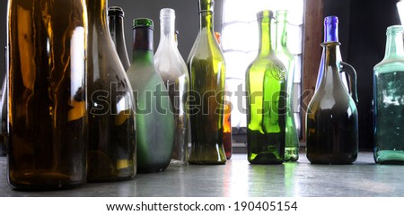 close-up colorful dusty bottles on a gray wooden floor in the studio on a background of light strip