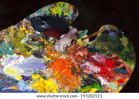 macro artist palette in hand, texture mixed oil paints in different colors and saturation studio