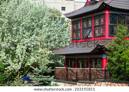 Spring cityscape building in the Japanese style on a background of a blossoming apple tree
