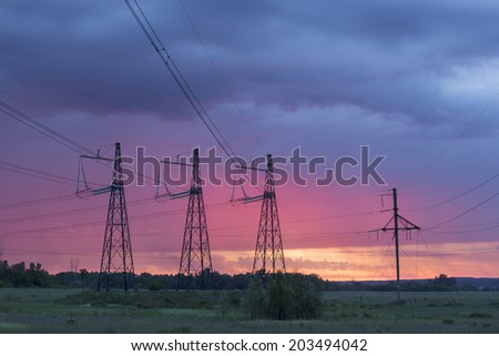 summer landscape high voltage power lines on sunrise background in the field near the woods