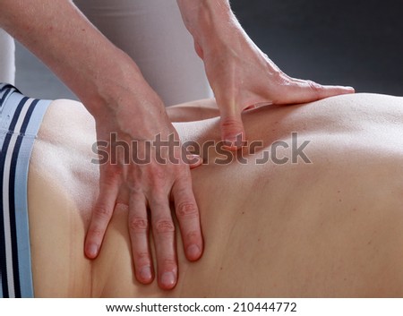 Isolated close-up of the hands of the masseur - female on man's back during a session, studio