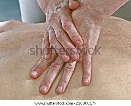 Isolated close-up of the hands of the masseur - female on man\'s back during a session, studio