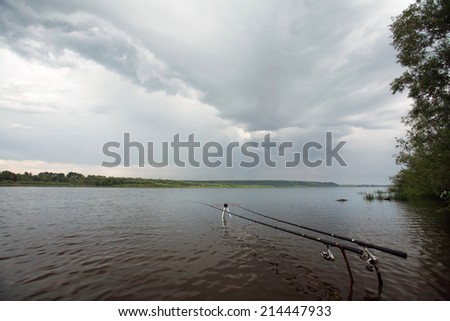 summer landscape storm clouds over the river and spinning on a stand near the shore