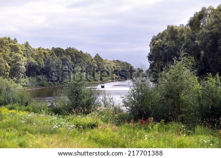 summer landscape boat on the river and densely tree-lined shores
