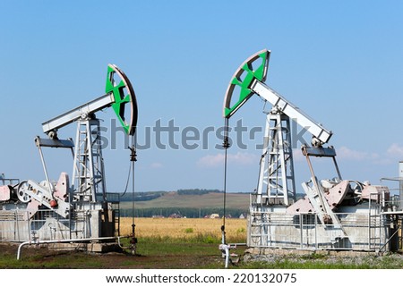 summer landscape oil pumps in the grain fields on the background of the blue sky on a sunny day