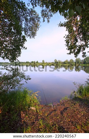 summer landscape glassy surface of a calm river and trees on the horizon in the early morning